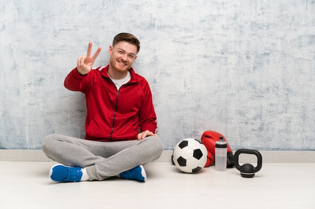 Uomo di sport di Redhead che sorride e che mostra il segno di vittoria