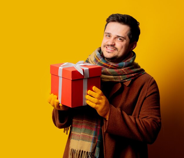 Uomo di stile in cappotto e sciarpa con confezione regalo