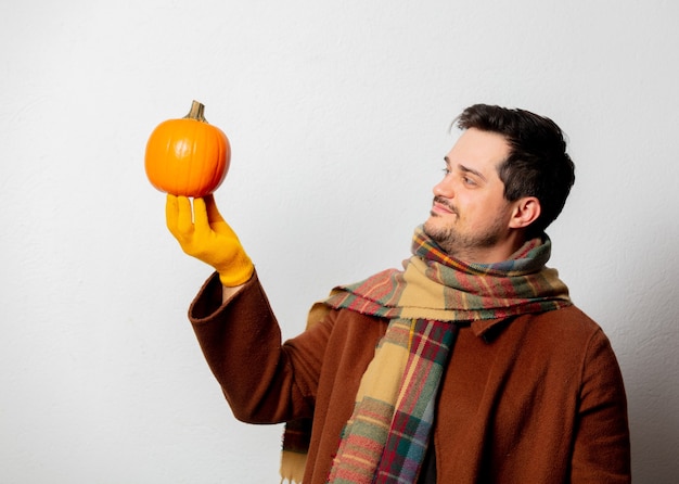 Uomo di stile in cappotto e sciarpa con zucca