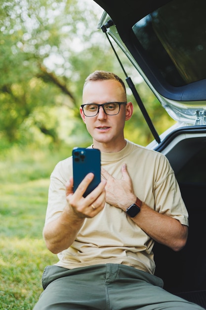 Uomo di successo che lavora all'aperto dalla sua auto seduto nel bagagliaio e guardando il laptop Concetto di stile di vita del lavoratore remoto online Spazio di copia