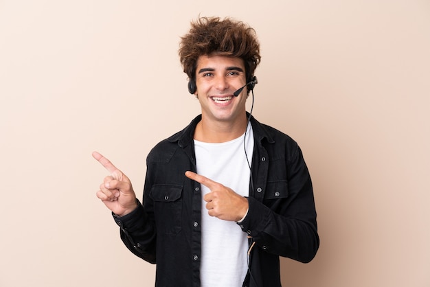 Uomo di Telemarketer che lavora con una cuffia sopra il muro isolato che punta il dito verso il lato