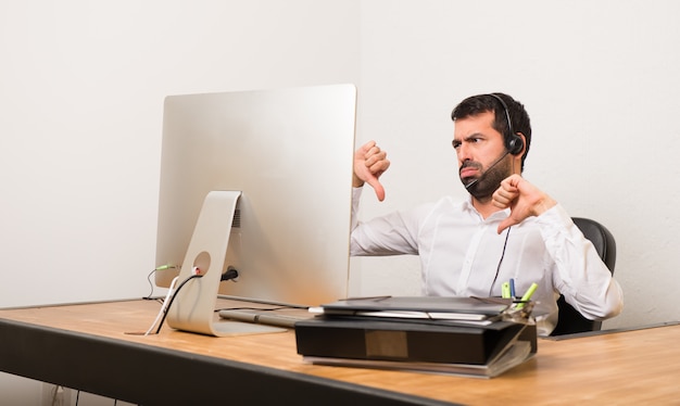 Uomo di Telemarketer in un ufficio che mostra pollice giù con entrambe le mani