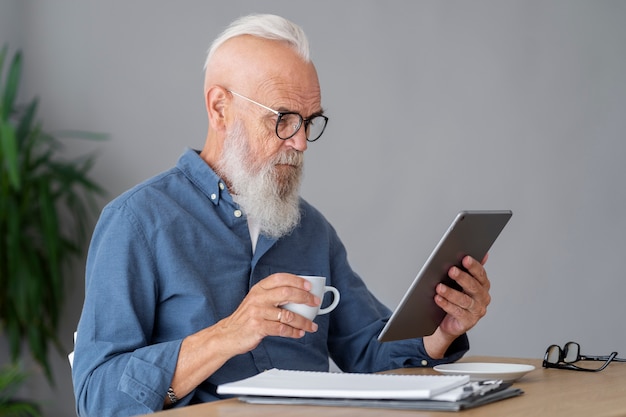 Uomo di tiro medio che studia alla scrivania con tablet