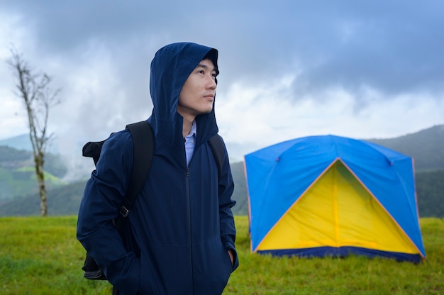 Uomo di viaggio felice che gode e si rilassa vicino alla tenda del campo