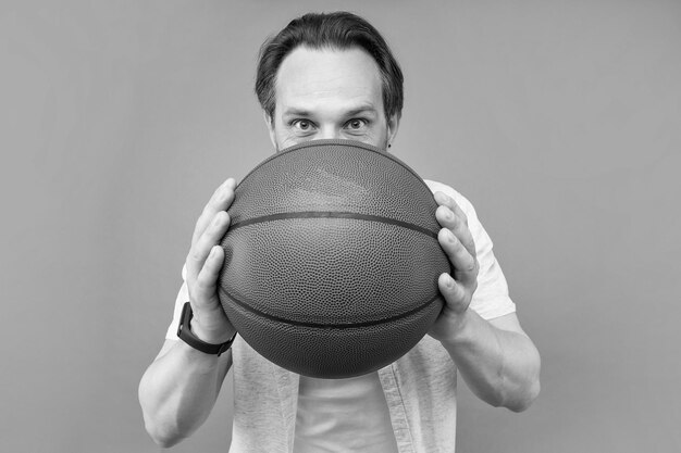 Uomo dietro la palla da basket su sfondo grigio gioco di sport
