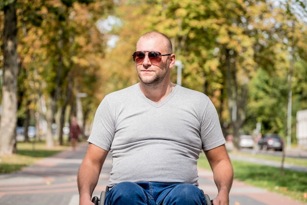 Uomo disabile in sedia a rotelle a piedi al vicolo del parco