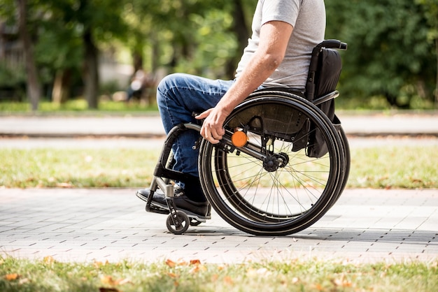 Uomo disabile in sedia a rotelle a piedi al vicolo del parco