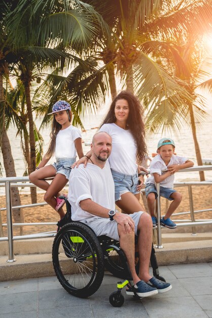 Uomo disabile in sedia a rotelle con la sua famiglia sulla spiaggia.