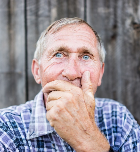 Uomo disperato senior che soffre e che copre il viso con le mani in profonda depressione