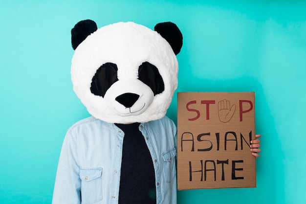 Uomo divertente che tiene un poster contro il razzismo asiatico