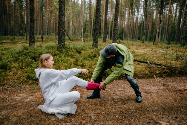 Uomo divertente che tira uno stivale rosa di donna divertente nella foresta