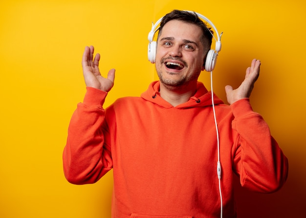 Uomo divertente con le cuffie sulla parete gialla