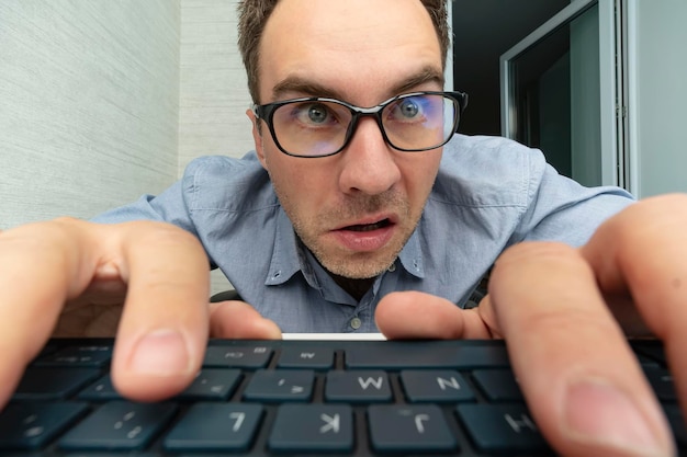 Uomo divertente e pazzo utilizzando un computer su sfondo bianco le mani dell'uomo sulla tastiera