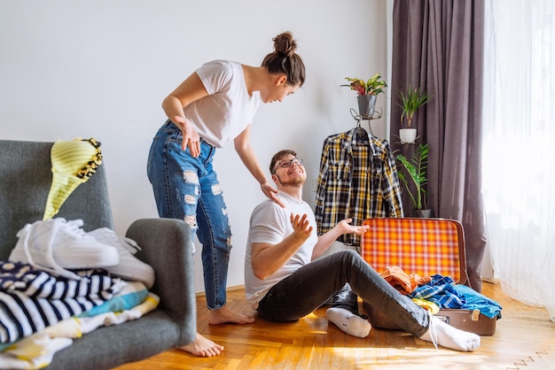 uomo donna ha bisogno di aiuto per fare le valigie concetto di viaggio uomo che cerca di adattare i vestiti nella borsa da viaggio