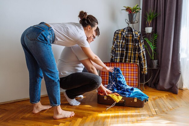 uomo donna ha bisogno di aiuto per fare le valigie concetto di viaggio uomo che cerca di adattare i vestiti nella borsa da viaggio