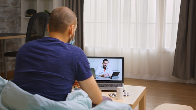 Uomo durante la quarantena del coronavirus che consulta il medico tramite videochiamata.