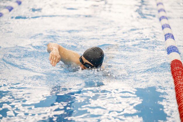 Uomo e cappello che nuotano nella piscina interna a rana