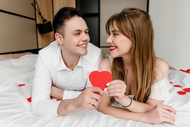 Uomo e donna a letto con a forma di cuore in mano