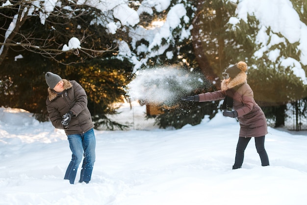 uomo e donna all'aperto durante una passeggiata invernale giocando a palle di neve e slittino