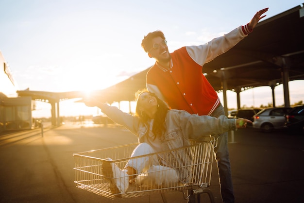 Uomo e donna alla moda che si divertono e cavalcano il carrello Concetto di lifestyle per il tempo libero giovanile