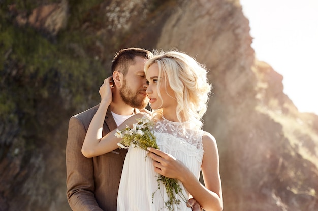 Uomo e donna amore e abbracci, relazione stretta e amore, coppia innamorata sulle rocce vicino al fiume, baci e coccole nello spruzzo d'acqua