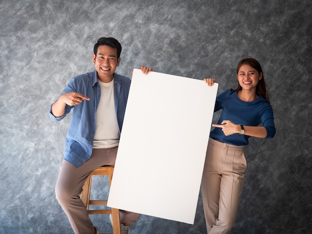 Uomo e donna asiatici con lo spazio bianco della copia dell'insegna