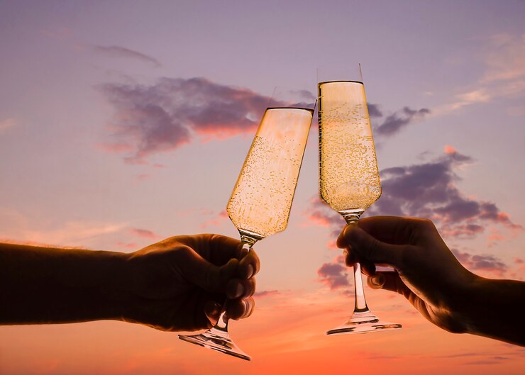 Uomo e donna brindano con champagne al tramonto