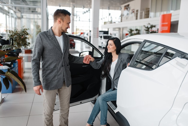 Uomo e donna che acquistano auto nuove in showroom.