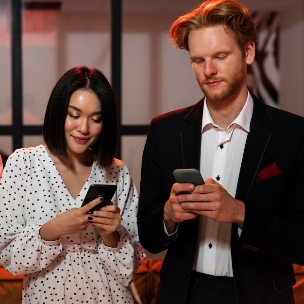 Uomo e donna che controllano i loro telefoni alla festa di capodanno