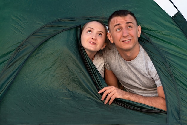 Uomo e donna che danno una occhiata dalla tenda turistica. Riposo in campeggio.