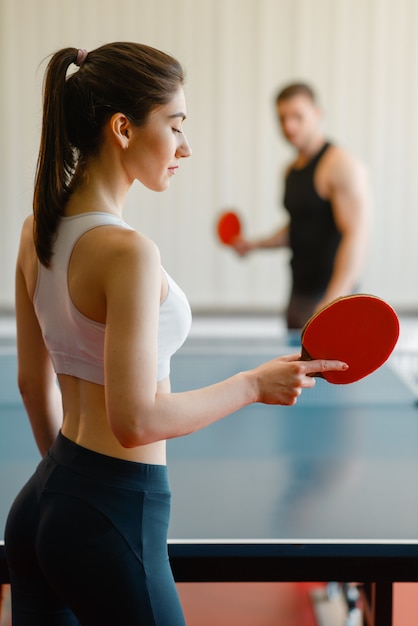 Uomo e donna che giocano a ping pong al chiuso