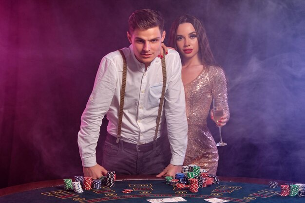 Uomo e donna che giocano a poker al casinò celebrando la vittoria al tavolo con pile di carte chip champagne