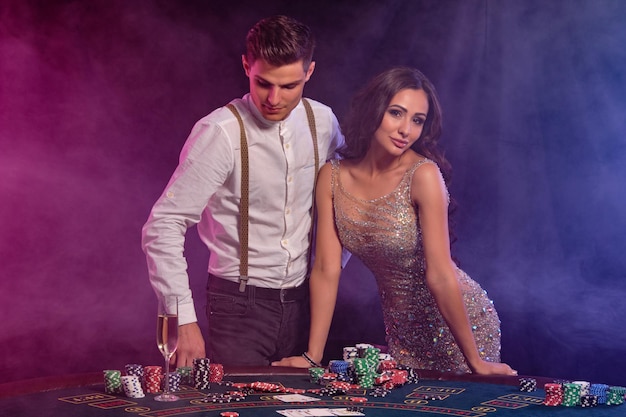 Uomo e donna che giocano a poker al casinò celebrando la vittoria al tavolo con pile di carte chip champagne