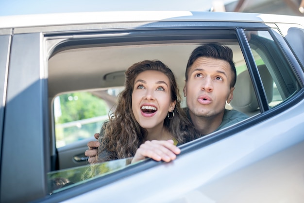 Uomo e donna che guardano da un finestrino della macchina