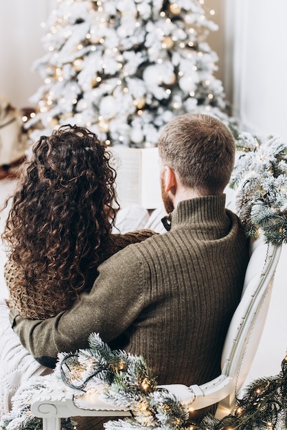 Uomo e donna che leggono insieme un libro sullo sfondo dell&#39;albero di Natale