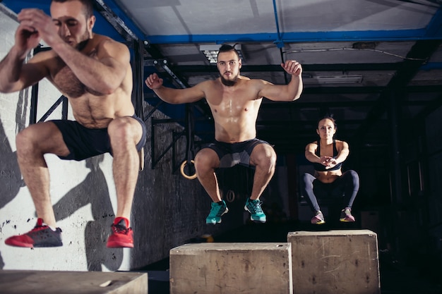 Uomo e donna che saltano sulla scatola in forma in palestra