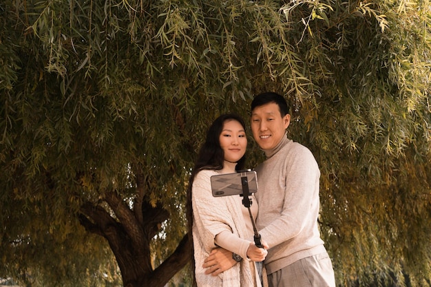 Uomo e donna che scattano foto selfie sotto il grande albero verde