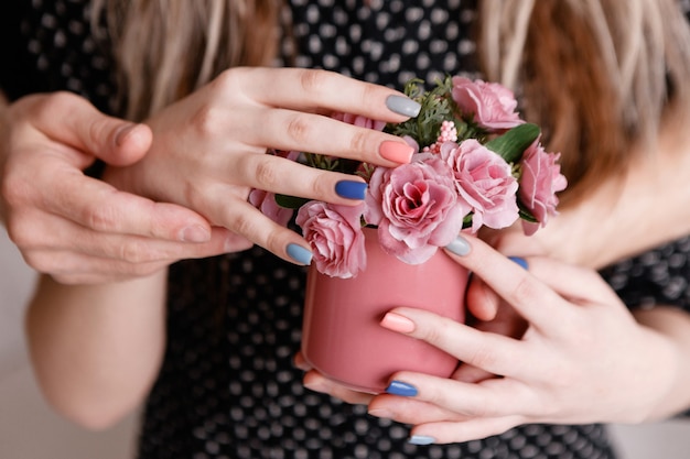 Uomo e donna che tengono insieme le rose nella tazza cremisi.