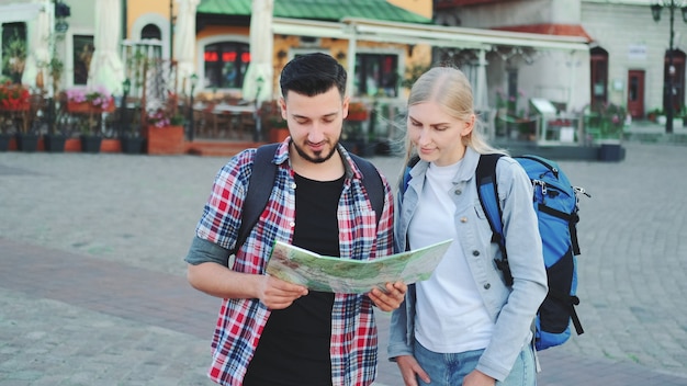 Uomo e donna che tengono la mappa e cercano un posto sulla piazza della città