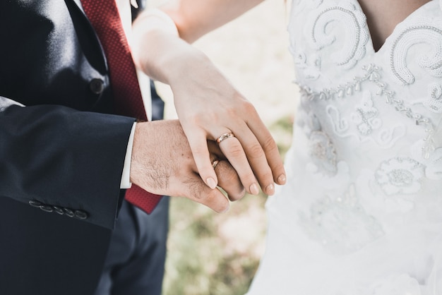 Uomo e donna che tengono le mani fedi nuziali sposa e sposo sullo sfondo