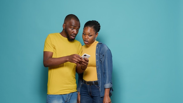 Uomo e donna che utilizzano internet sullo smartphone insieme davanti alla telecamera. Persone che guardano il display del telefono cellulare e hanno una connessione positiva. Coppia moderna che lavora con la tecnologia.