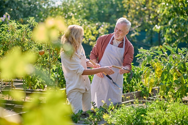 Uomo e donna con attrezzi da giardino in giardino