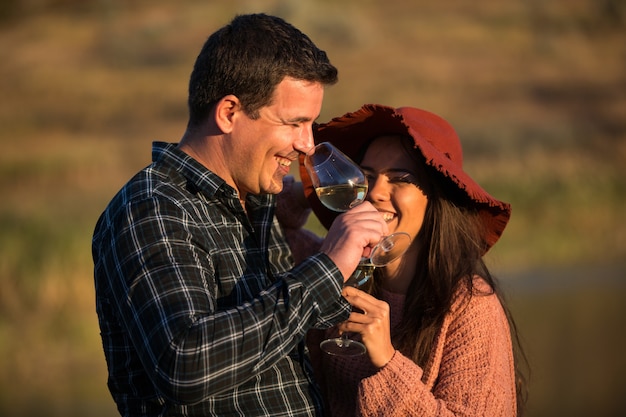 Uomo e donna con bicchieri di vino in mano sul tramonto in un vigneto.
