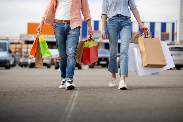 Uomo e donna con borse nel parcheggio del supermercato