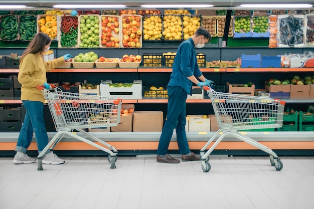 Uomo e donna con carrelli della spesa in un supermercato durante il periodo di quarantena. foto con copia-spazio