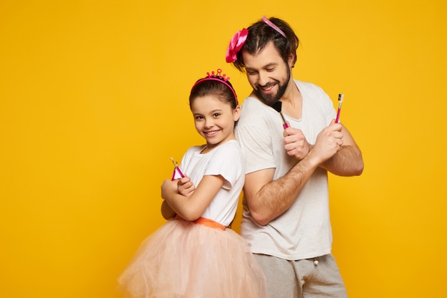 Uomo e donna con le armi Akimbo che tiene l'attrezzatura per il trucco.