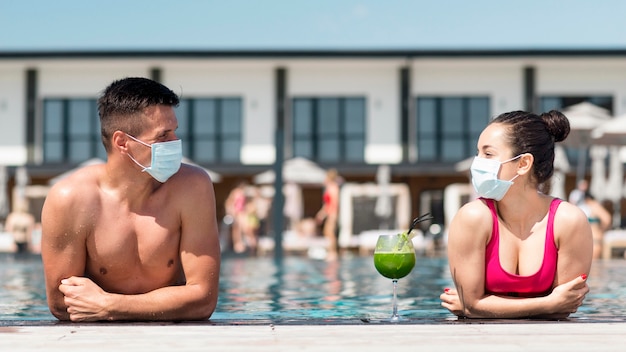 Uomo e donna con maschera mantenendo la distanza sociale