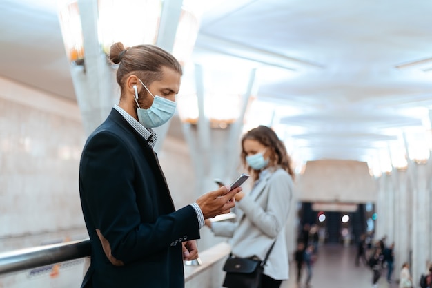 Uomo e donna con maschere protettive in attesa di un treno nella metropolitana