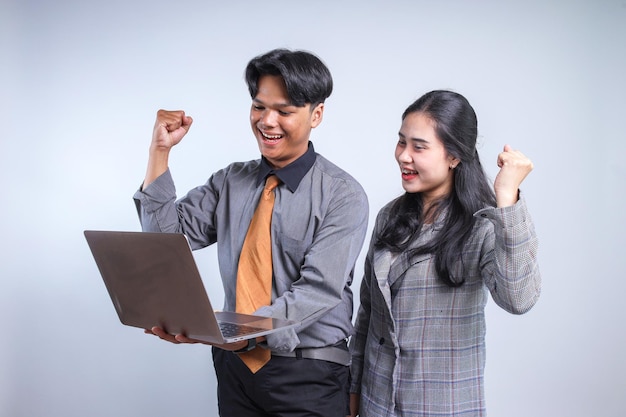 Uomo e donna d'affari asiatici che guardano il portatile e stringono il pugno per festeggiare il loro successo