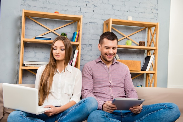 Uomo e donna di mentalità felice che lavorano su laptop e tablet